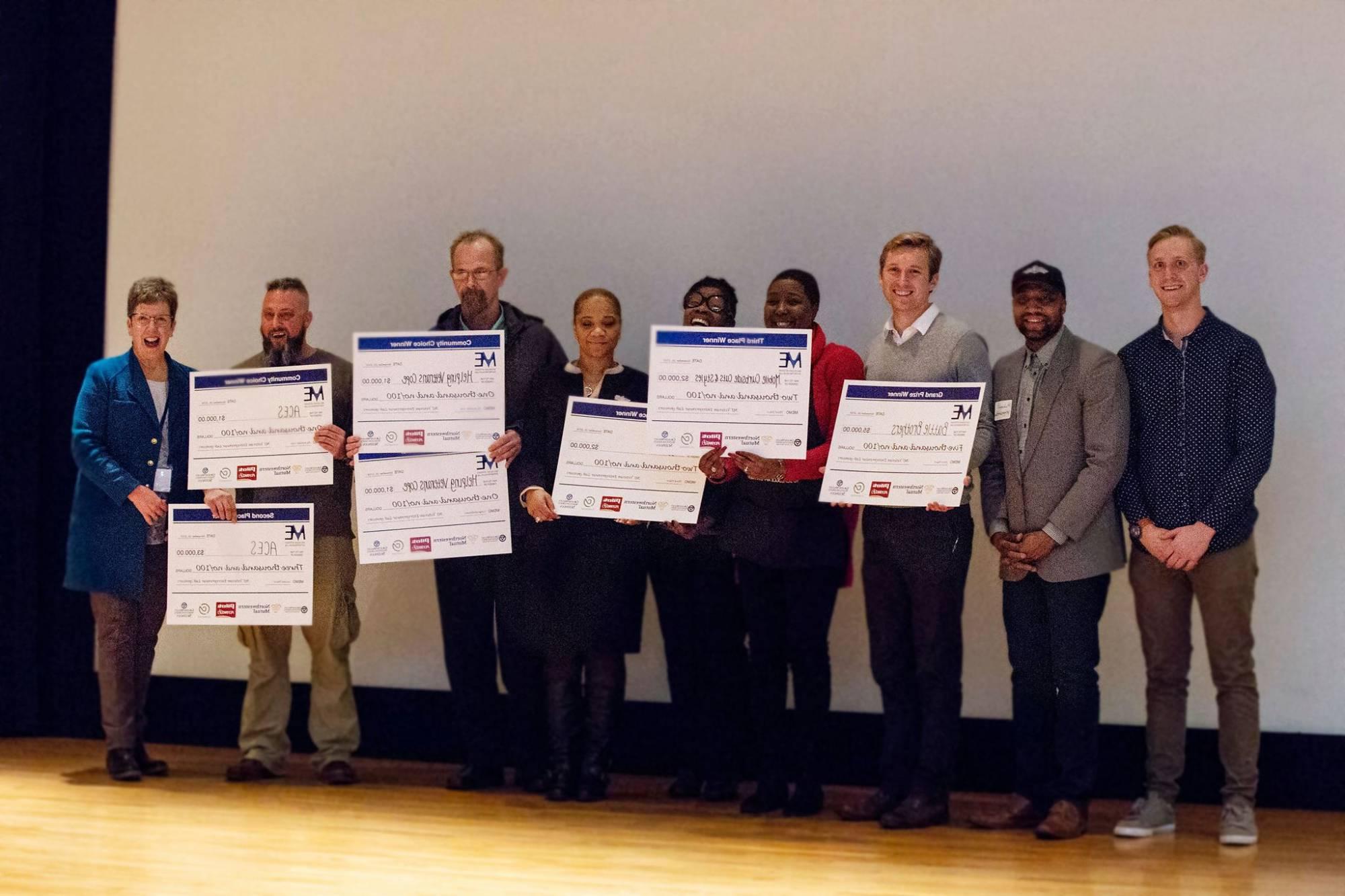 winners of pitch competition holding presentation checks